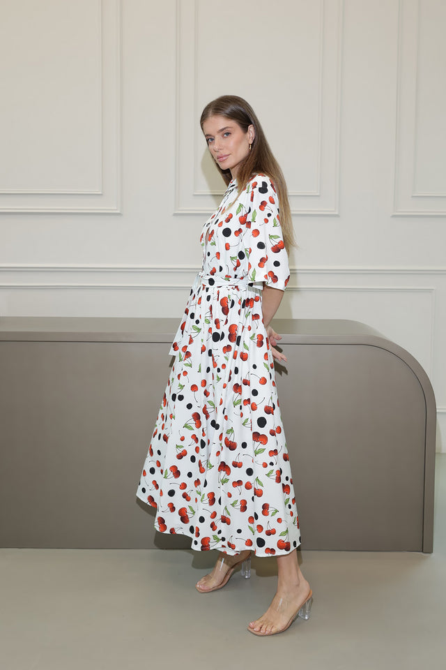 Woman wearing a long, patterned dress standing against a neutral background
